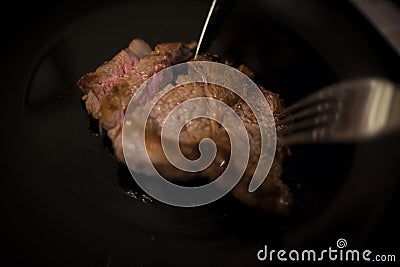 Piece of beef tenderloin to be cut into black dish Stock Photo