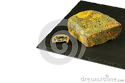 Piece of black bread with green mold and a piece of kiwi with a mold on a black shale board isolated on white background, concept Stock Photo