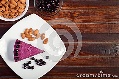 A piece of blackcurrant cake on a white plate on a wooden background Stock Photo