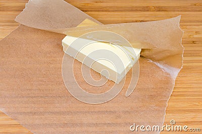 Piece of butter in waxed paper on a wooden surface Stock Photo
