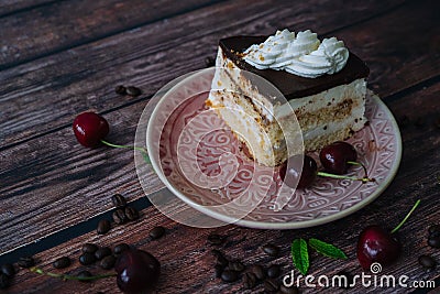 Piece of cake with cream on plate. Chocolate cake on wooden background with coffee beans and mint leaves. Delicious slice of Stock Photo