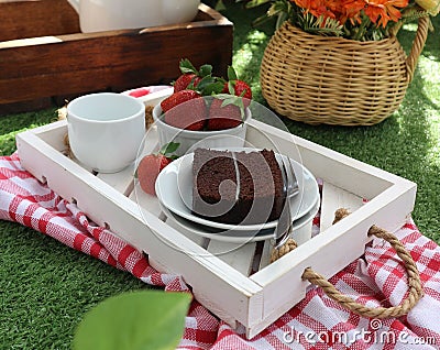 a piece of chocolate cake, a bowl of strawberries and a cup of tea Stock Photo