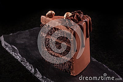 Piece of chocolate cake. Chocolate mousse cake slice on a black board, black background. Stock Photo