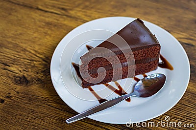 Piece of chocolate cake with spoon on white plate Stock Photo