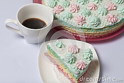 The piece is cut off and lies side by side on a saucer. Nearby is a cup of coffee. Waffle cake made from cream soaked cakes. Stock Photo