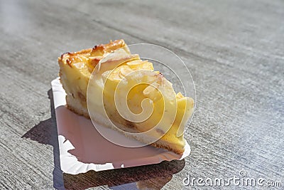 Piece of fresh apple pie with almonds on a cardboard on a table in the sun, delicious summer dessert, copy space, selected focus Stock Photo