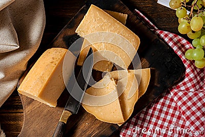 Piece of a last of Italian provolone cheese and freshly cut fetas on the board. Top view Stock Photo