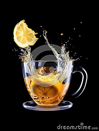 A piece of lemon and orange falls into a glass of water and splashes fly in all directions Stock Photo