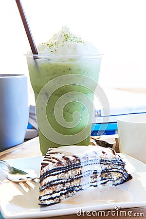 piece of mable cake with vanilla cream and cool green tea in glass on table top shot Stock Photo