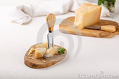 Piece of parmesan cheese on wooden board on white background. Parmigiano Reggiano, hard mature cheese Stock Photo