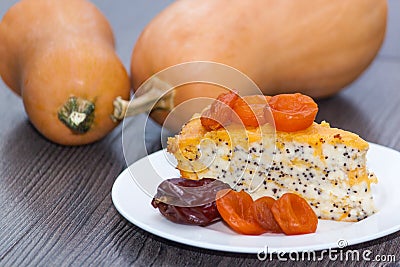 Piece of pumpkin homemade cheesecake with dried apricots, poppy, orange, date fruit on the wooden table. Thanksgiving Day. Stock Photo