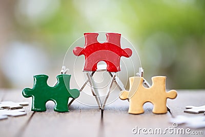 Piece of Red green and gold jigsaw puzzle On the old wood And green background. teamwork concept. symbol of association and Stock Photo