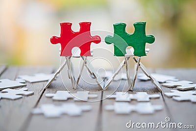 Piece of Red and green jigsaw puzzle On the old wood And green background. teamwork concept. symbol of association and Stock Photo