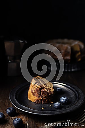 Piece of served chocolate and vanilla marble bundt cake with blueberries and coffee Stock Photo