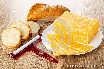 Piece and slices of bread, cheese cutter, slices of cheese, piece of marble cheese in plate on table Stock Photo