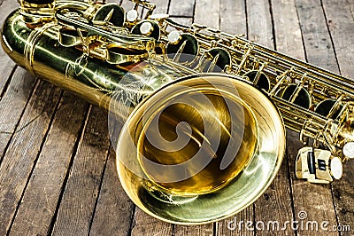 Piece of yellow saxophone - bell and valves on a vintage wooden surface Stock Photo