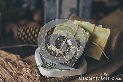 Pieces of beautiful natural handcrafted soap on wooden background with botanical elements, close up view. Stock Photo