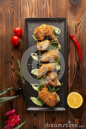Pieces of chicken in batter on a black plate on a wooden background Stock Photo