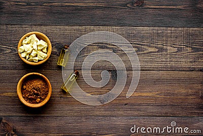 Pieces of cocoa butter and cacao powder in bowl for homemade cosmetics. Dark wooden background top view copy space Stock Photo