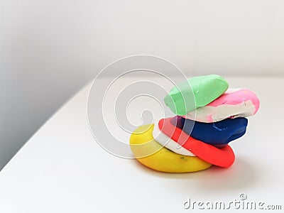 Pieces of colored plasticine collected in a pyramid on a white table Stock Photo