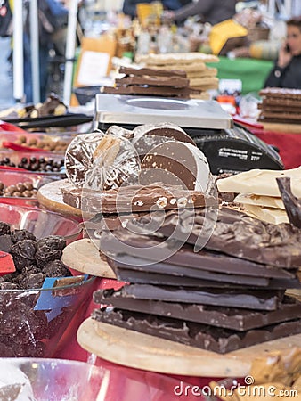 pieces of crude chocolate with hazelnuts stacked on wooden chopping boards. In the background other pieces of mixed chocolate. Re Stock Photo