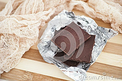 Pieces of dark broken chocolate in wrapping foil Stock Photo