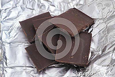 Pieces of dark broken chocolate on wrapping foil Stock Photo