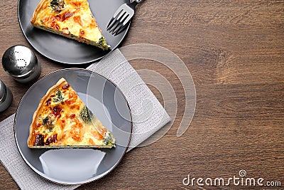 Pieces of delicious homemade salmon quiche with broccoli, fork and salt shaker on wooden table, flat lay. Space for text Stock Photo