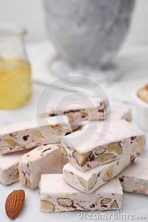 Pieces of delicious nutty nougat on white table, closeup Stock Photo