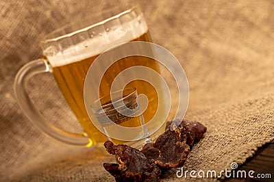 Pieces of dried caviar, a glass of vodka and a mug of beer on a table covered with a homespun cloth with a rough texture Stock Photo