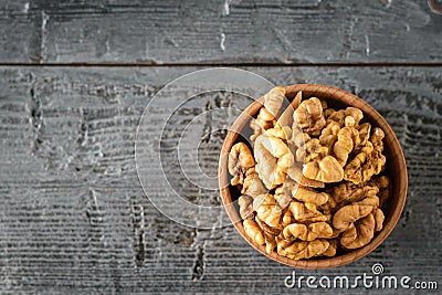 Pieces of peeled walnut in a wooden bowl on a dark wooden table. The view from the top Stock Photo