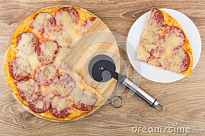 Pieces of pizza with sausage, pepper and cheese and cutter on cutting board Stock Photo