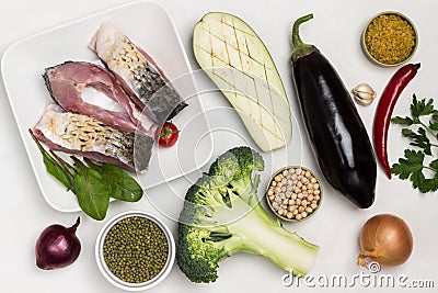 Pieces of river carp fish in plate. Eggplant, broccoli and groats on table Stock Photo