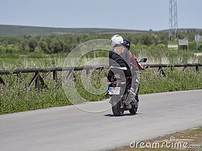 Piedra de Fuente, Spain-28th April 2019:A Young Spanish Couple, on a Motorbike with the Woman riding Pillion, driving down a road. Editorial Stock Photo