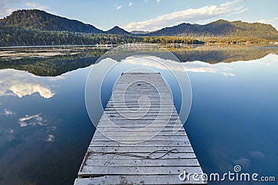 Pier on the lake on the background of sunset in a clear summer day. Warm summer evening on the dock. Fabulous views of the lake Stock Photo