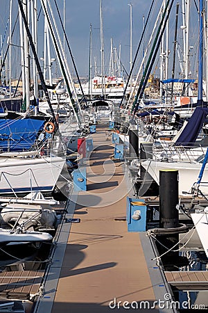 Pier with many parking yachts in calm marina water on bright summer day Stock Photo