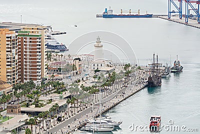 Pier one in the port of Malaga, Spain where is the lighthouse known as `La Farola` and several docked ships, including a galleon, Editorial Stock Photo