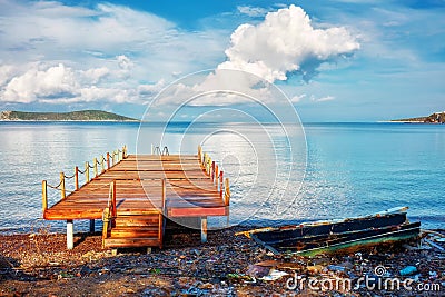 Pier and a stranded boat wreck beached on the sea shore Stock Photo