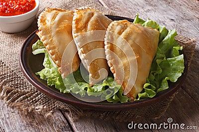 Pies empanadas on a plate with lettuce and sauce, horizontal Stock Photo