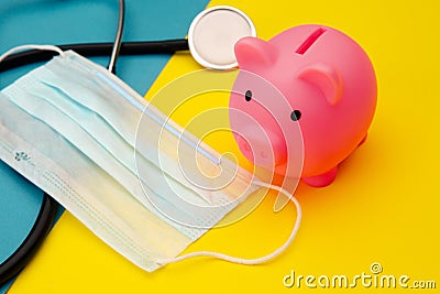 Pig moneybox in pink color, face mask and stethoscope on colorful background. Spending money on pills and expensiveness Stock Photo