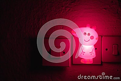 Pig Night Light. Small pink light for night . Cute Peppa pig lighting in the room. Plug in night light Editorial Stock Photo