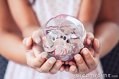 Piggy bank in child kid and mother hands Stock Photo