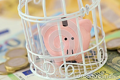 Piggy bank closed in a cage on euro money - Concept of savings blocked Stock Photo