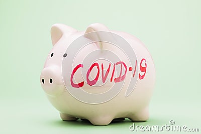 Piggy bank with an inscription on a green background. The concept of lack of money during quarantine due to the Covid-19 pandemic Stock Photo