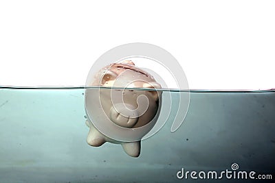 A piggy bank sinks in dark murkey water, representing the idea of drowning in debt, or keeping your head above water and other Stock Photo