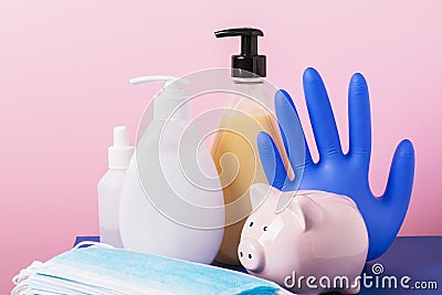 Piggy bank and various personal protective equipment on a pink background. Hygiene spending concept during coronavirus pandemic Stock Photo