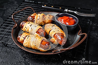 Pigs in Blanket puff pastry sausage wrap roll. Black background. Top view Stock Photo