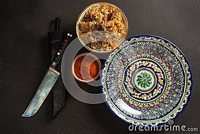 Pilaf is a traditional rice dish with lamb or beef and vegetables in ethnic Uzbek ceramic dishes. Stock Photo