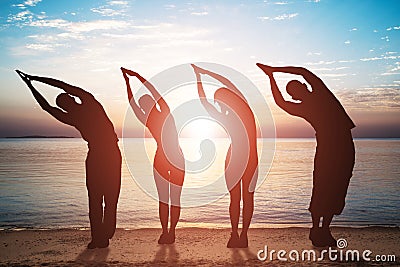 Group Of People Doing Stretching Exercise On Beach Stock Photo