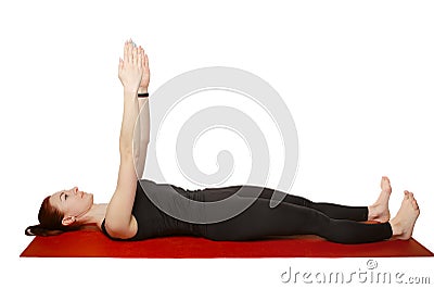 Pilates or yoga. A slender athletic girl lies on her back on a mat with her hands raised in the air. Stock Photo